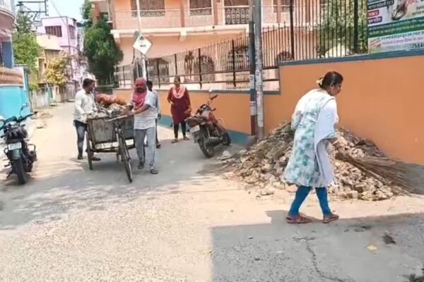 Councilor and her husband cleaning up garbage with brooms in hand