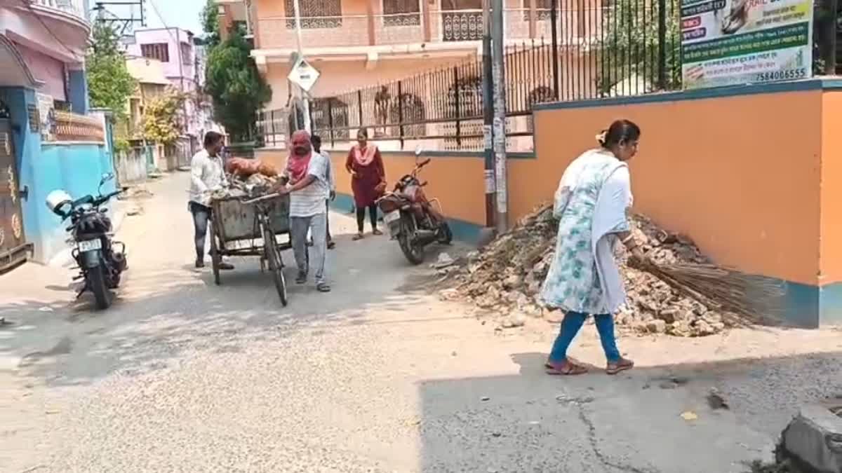 Councilor and her husband cleaning up garbage with brooms in hand